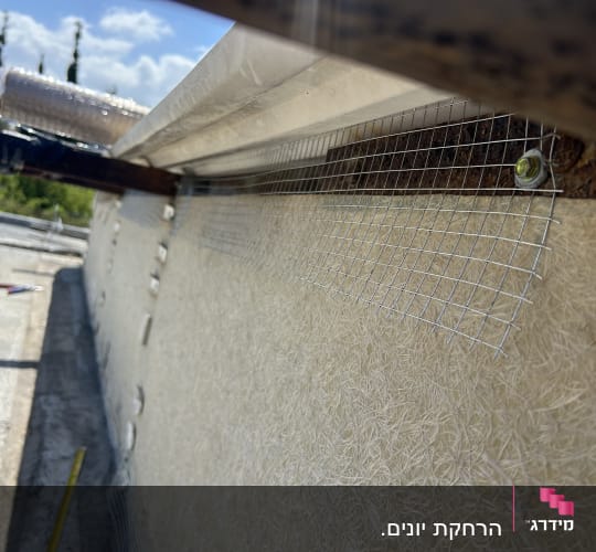 רשת מתכת מותקנת על קיר חיצוני למניעת יונים